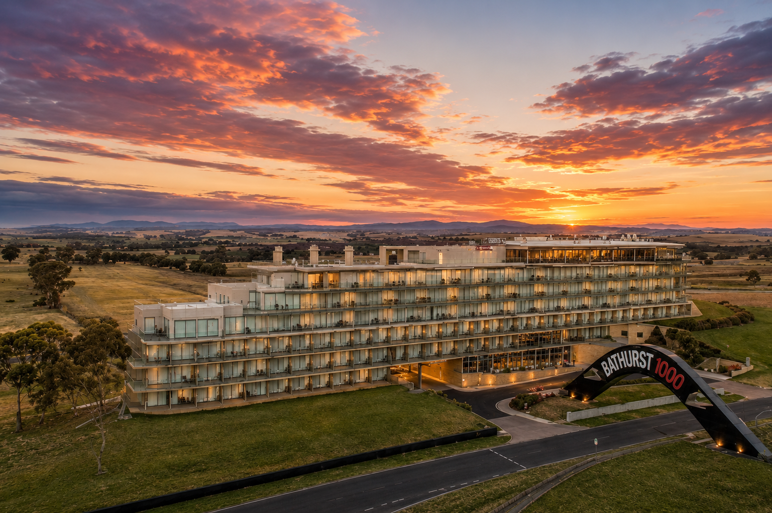 Aerial sunset view of Rydges Mount Panorama hotel beside the Bathurst 1000 arch, Bathurst NSW