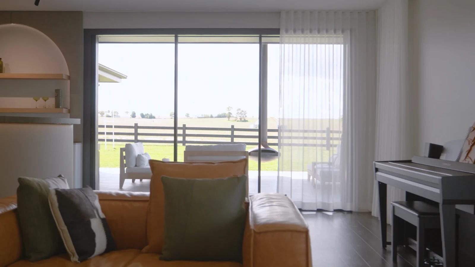 S-fold sheer curtains across sliding doors in an open-plan living room looking out to paddocks, by Quicksew
