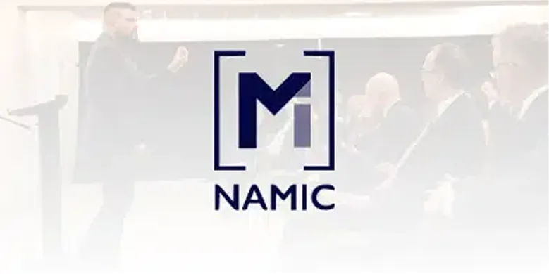 NAMIC logo over a photo of a speaker addressing a conference audience