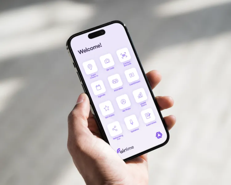 Hand holding a phone showing an AirTime event app home screen with check-in, agenda and networking tiles