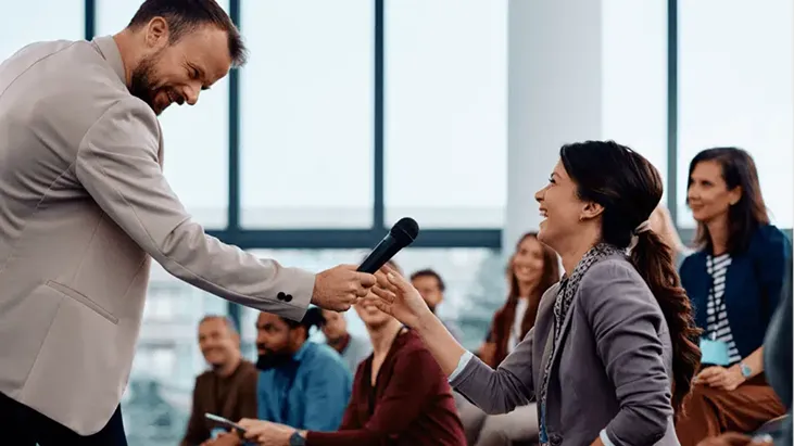 Speaker handing a microphone to an audience member during a session Q and A