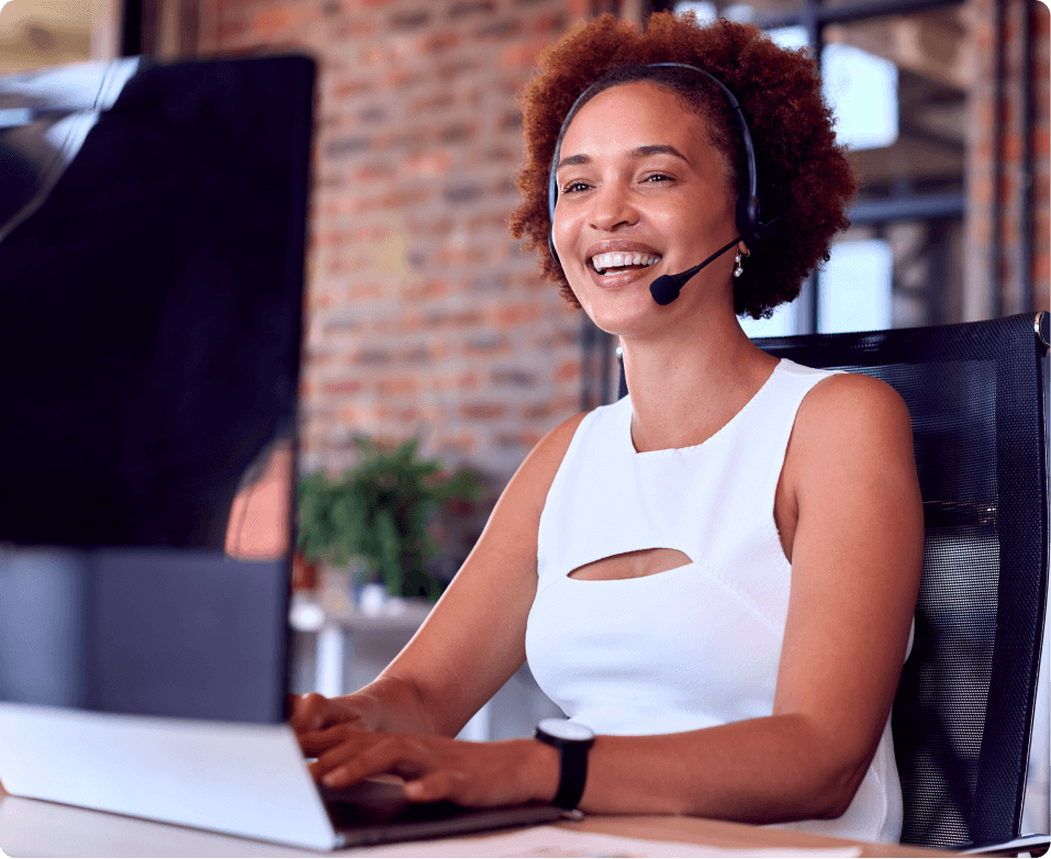 Smiling support agent wearing a headset working at a computer