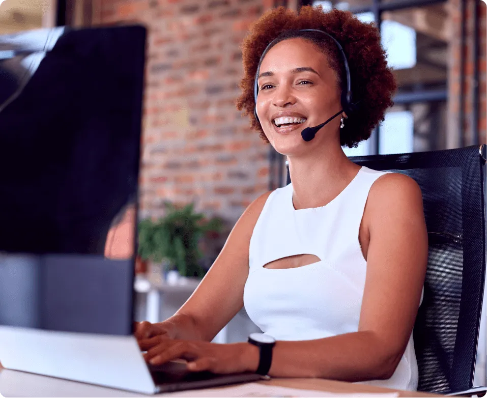 Smiling support agent wearing a headset working at a computer