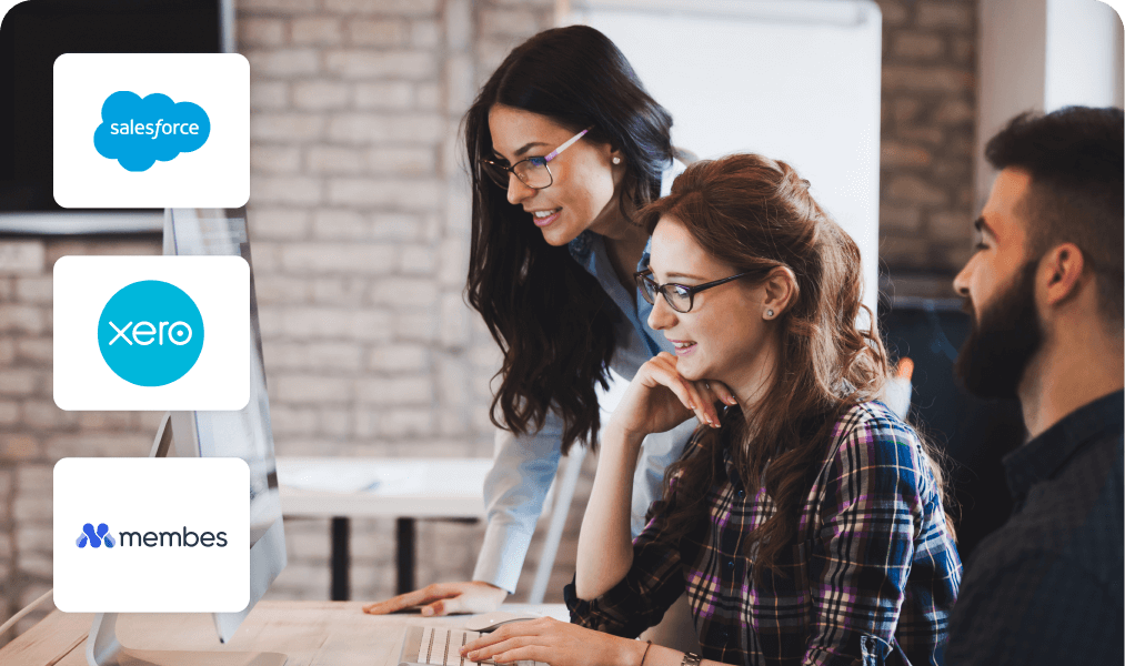 Colleagues working at a computer, with Salesforce, Xero and Membes integration logos alongside