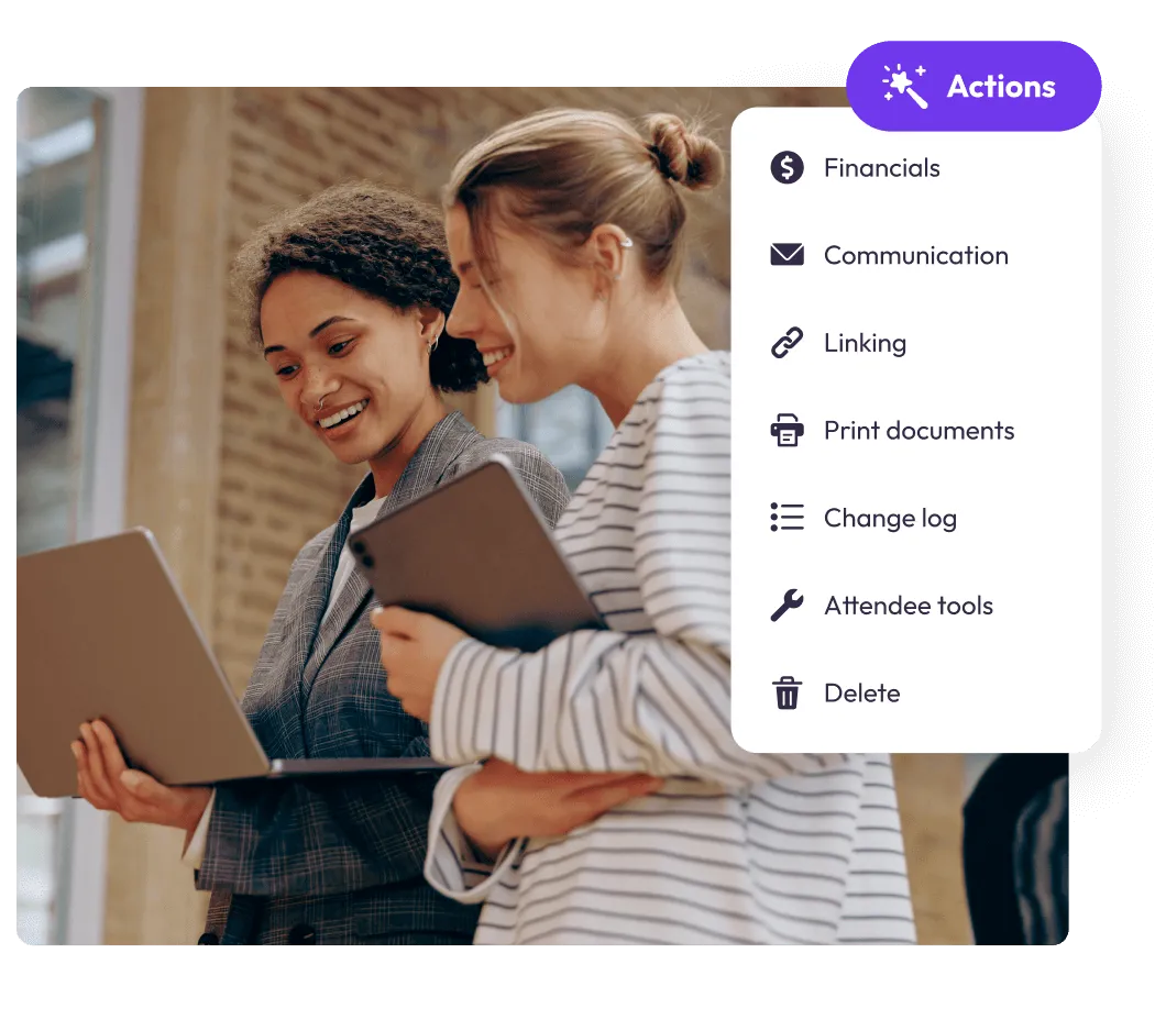 Two event planners looking at a laptop beside an attendee record Actions menu of financials, communication and attendee tools