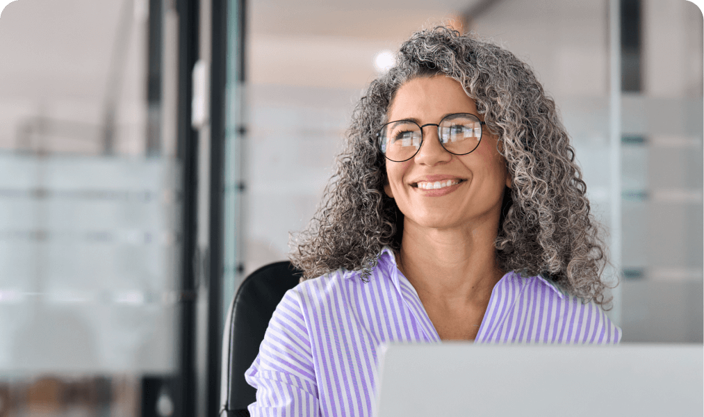 Event professional smiling while working at a laptop in an office