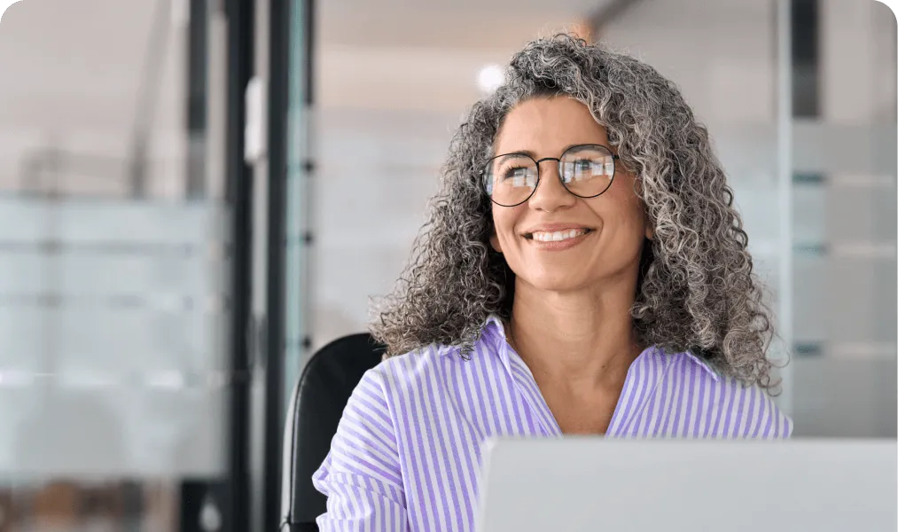 Event professional smiling while working at a laptop in an office