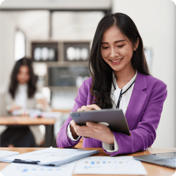 Event planner in a purple blazer smiling while using a tablet at a desk