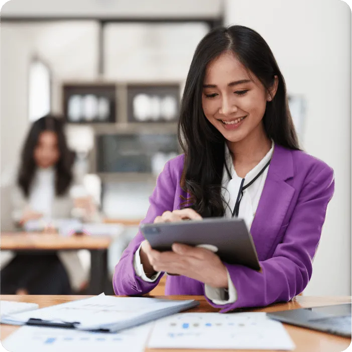Event planner in a purple blazer smiling while using a tablet at a desk