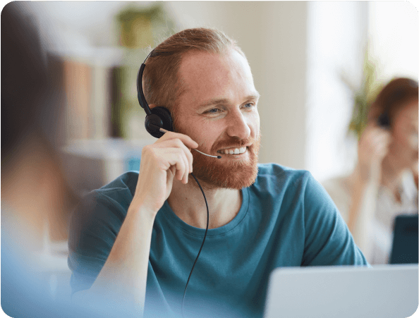 Smiling support specialist wearing a headset at a laptop in an office