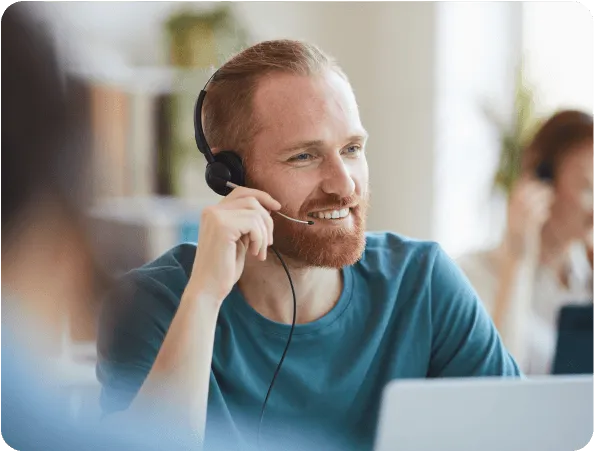 Smiling support specialist wearing a headset at a laptop in an office