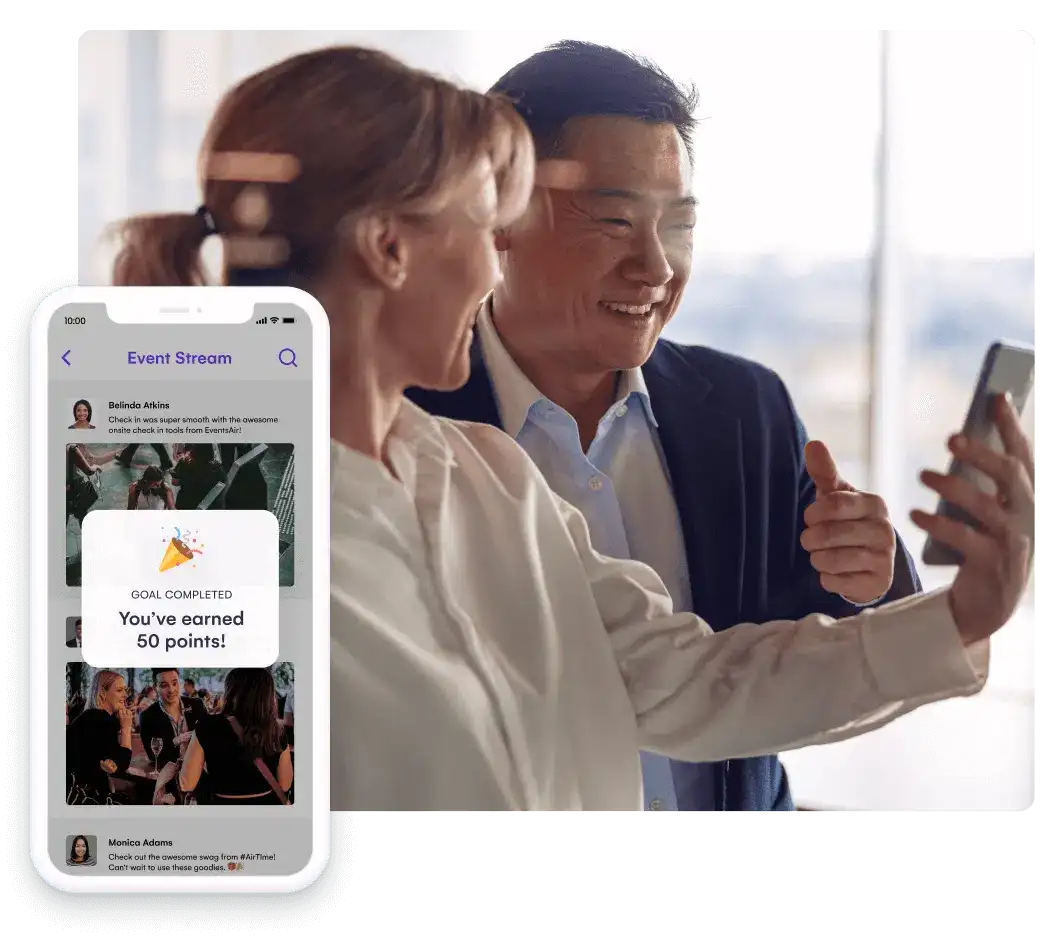 Two attendees taking a selfie beside a phone showing the Event Stream feed and a goal completed reward