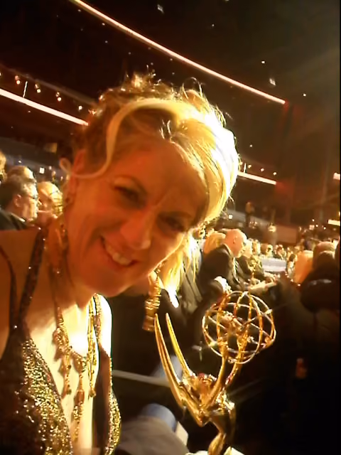 Solange Schwalbe holding an Emmy Award at an awards ceremony.