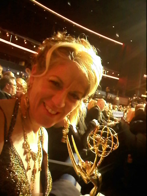 Solange Schwalbe holding an Emmy Award at an awards ceremony.