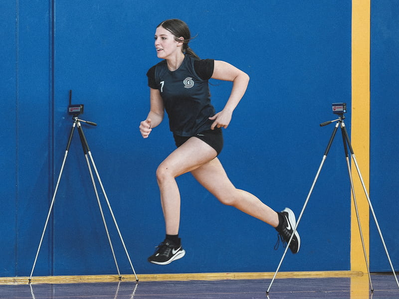 Athlete sprinting through electronic timing gates during a speed test
