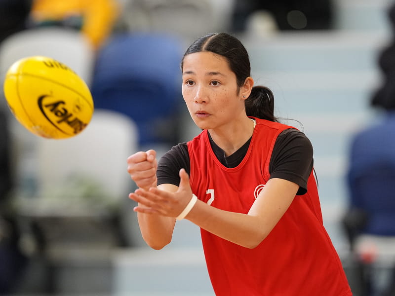 Young female athlete practicing a pass with an AFL ball