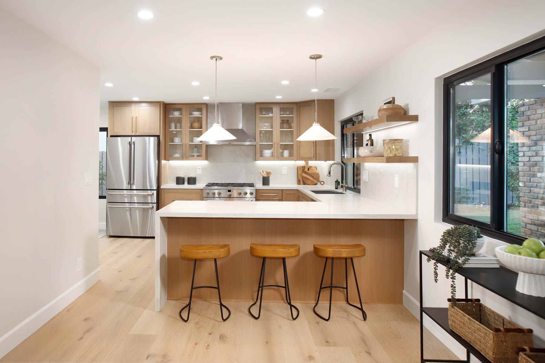 Remodeled kitchen with peninsula bar seating and West Elm pendant lights at 19939 Hemmingway Street, Winnetka