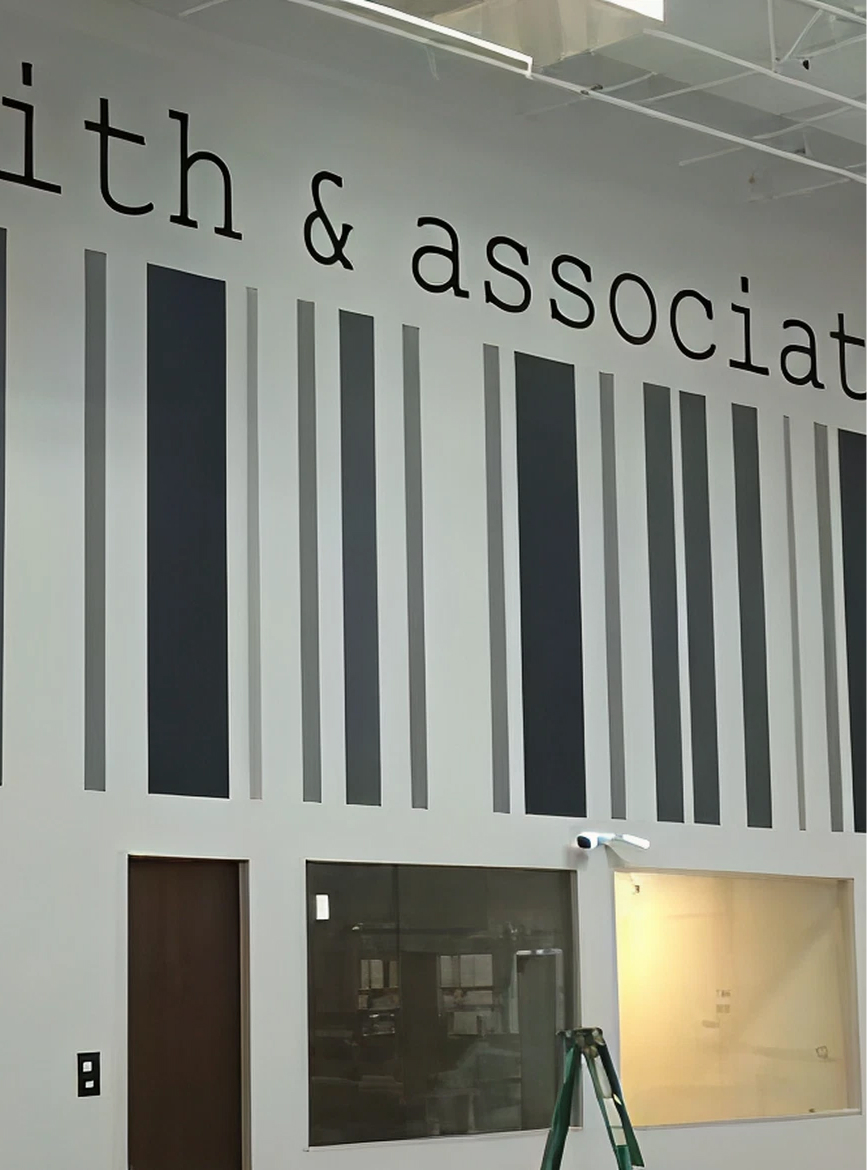 Interior wall with partial text 'ith & associat', vertical black and gray stripes, a door, window, and ladder.