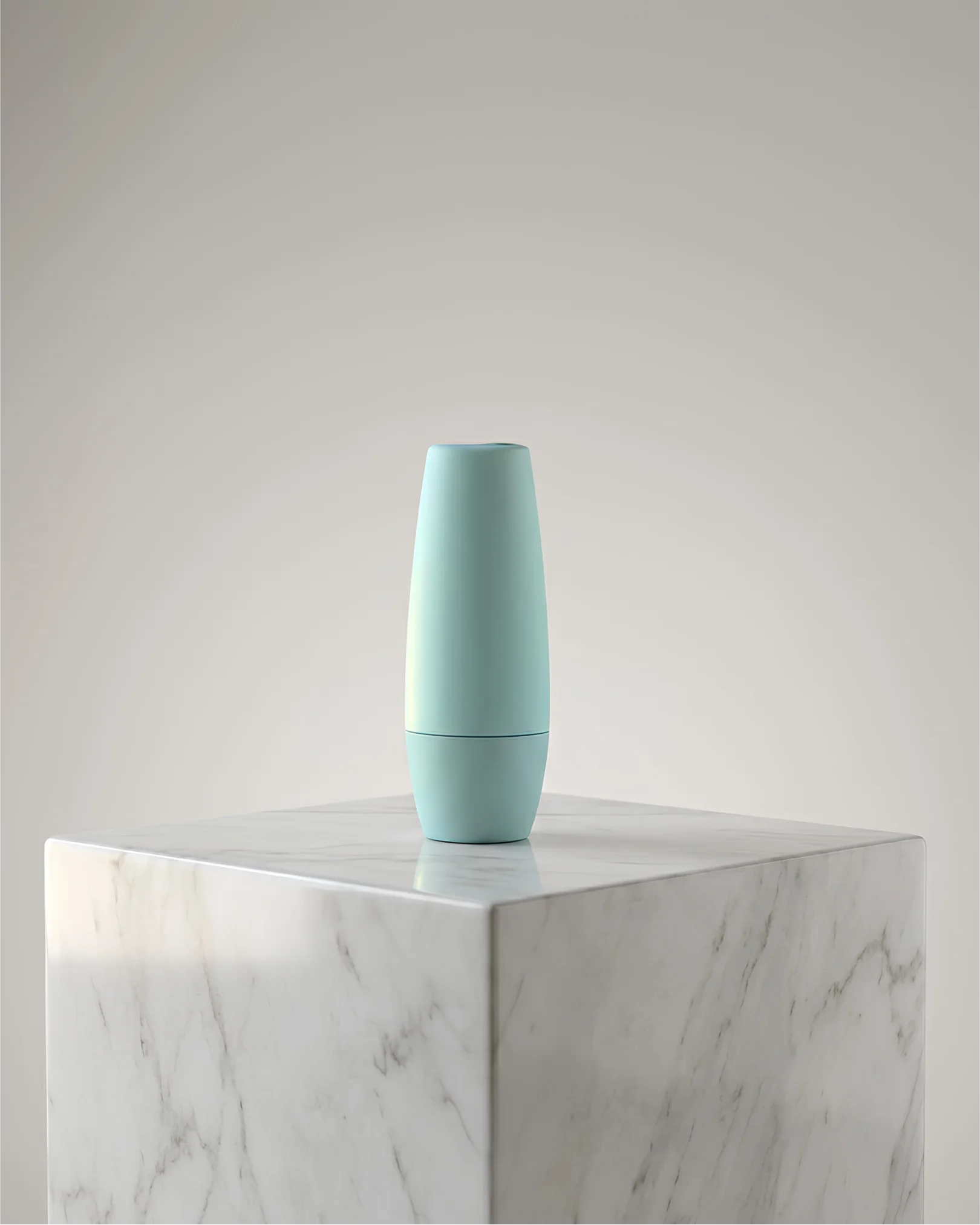 Minimalist matte terracotta cylindrical bottle placed on a concrete pedestal with diagonal shadows.
