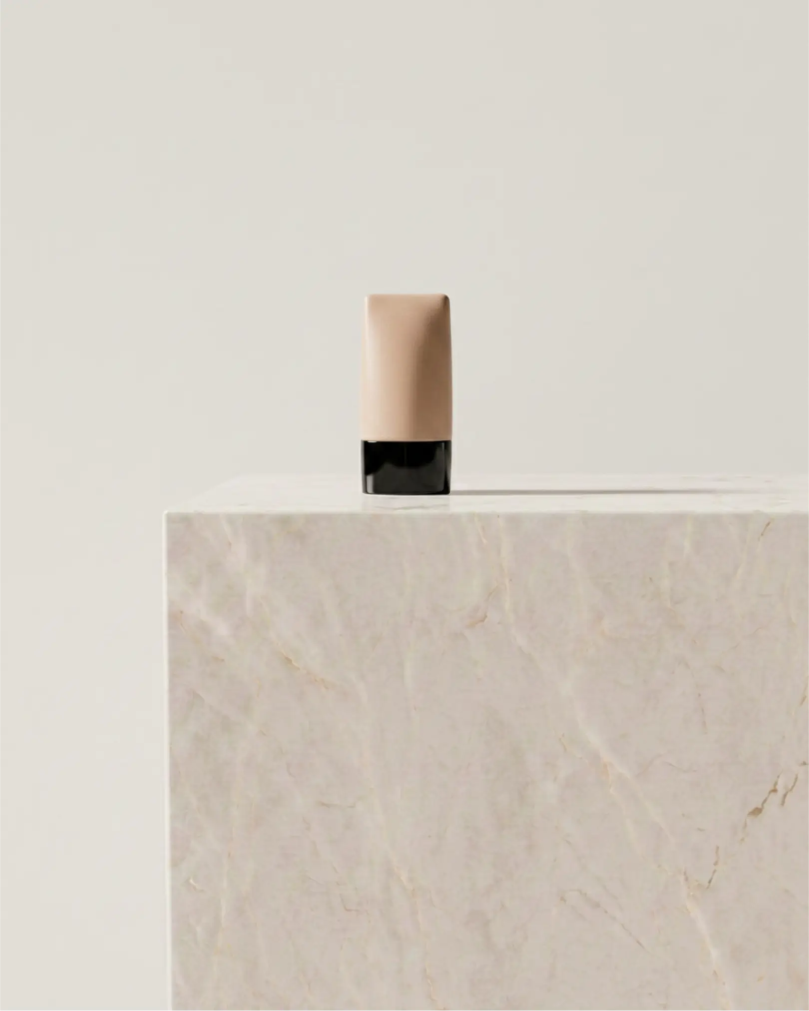 Minimalist matte terracotta cylindrical bottle placed on a concrete pedestal with diagonal shadows.