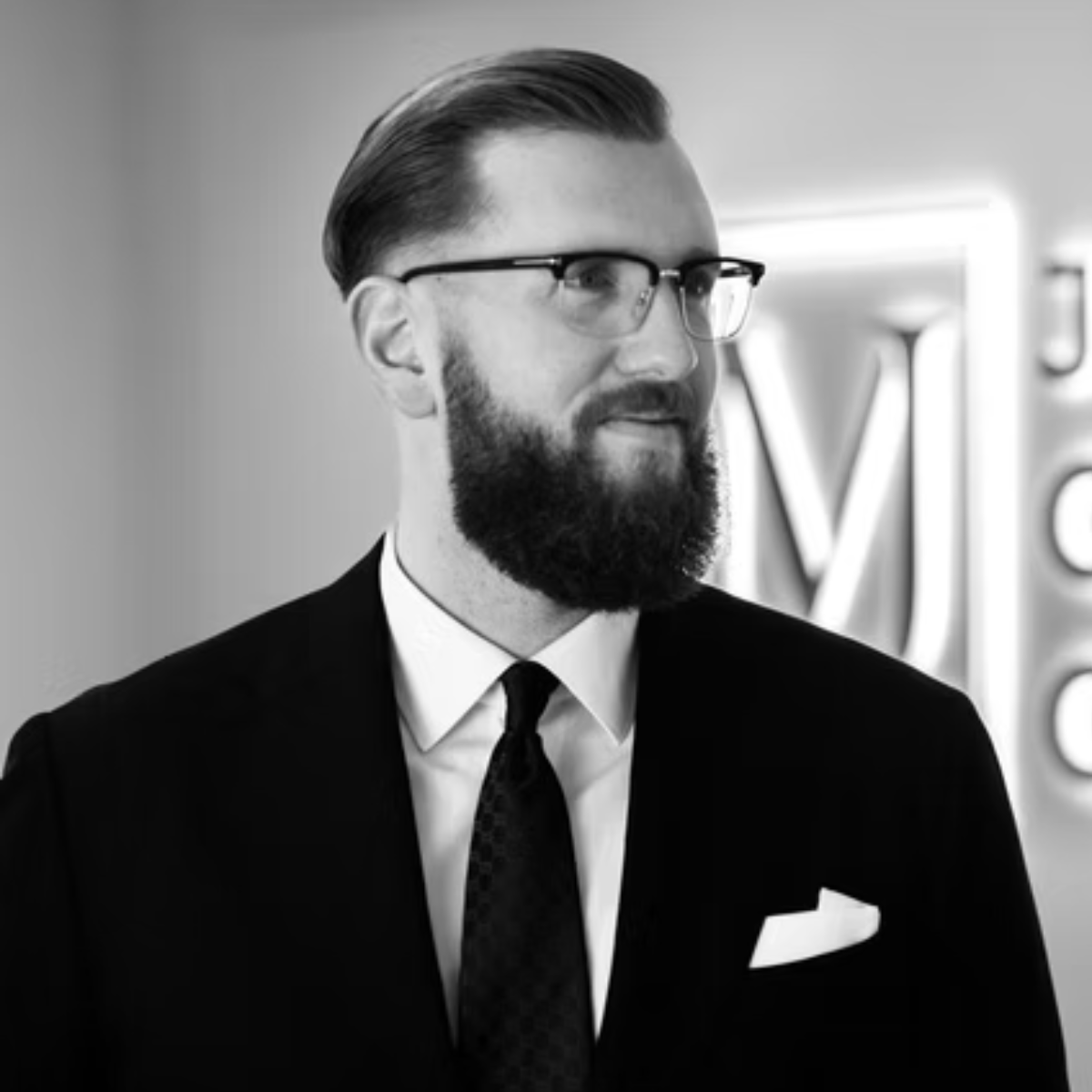 Maximilian Jäger in a suit and tie looking to the side, black and white photo.