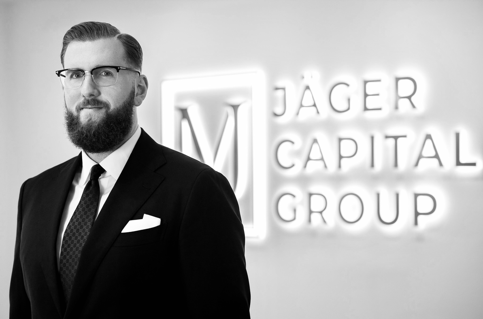 Maximilian Jäger standing in front of illuminated Jäger Capital Group sign.