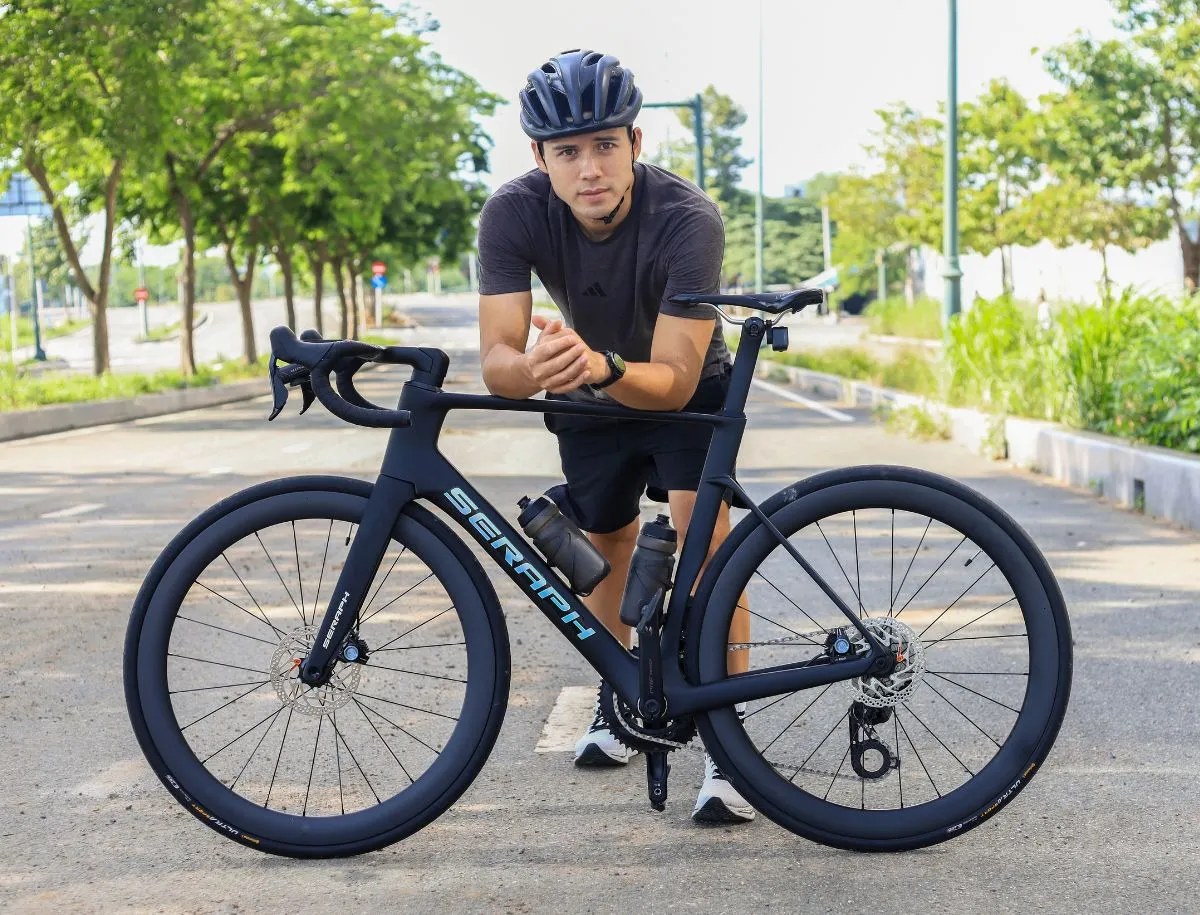 Mike Dee posing with the Seraph TT-X71 carbon road bike on a paved road