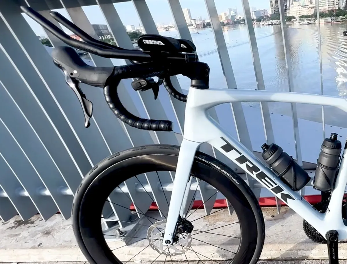 Trek Domane SL5 configured for triathlon with Profile Design Sonic Ergo 39a aerobars, Elitewheels deep-section carbon disc brake wheels, two water bottles, and Continental GP 5000 S TR tubeless tyres, parked by waterfront