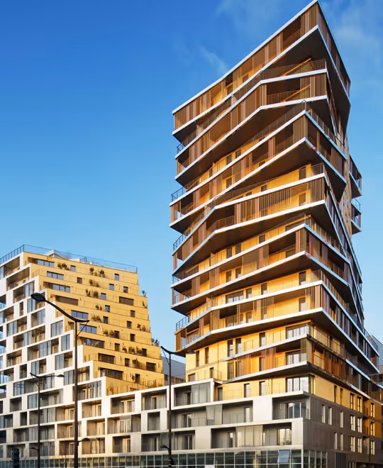 Modern high-rise apartment buildings featuring dynamic, multi-angled gold and bronze architectural cladding panels.