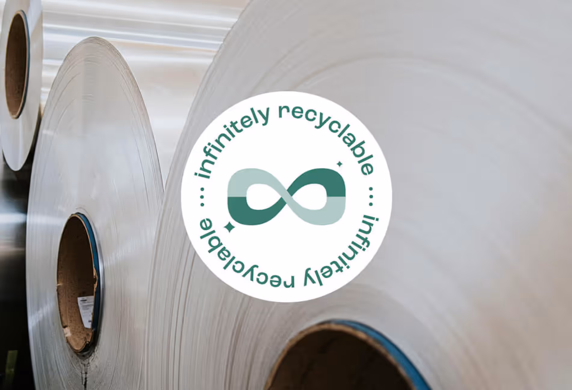 Close-up of wound metal rolls with a circular badge reading infinitely recyclable, highlighting the eco-friendly lifecycle of Euramax aluminium cladding solutions.