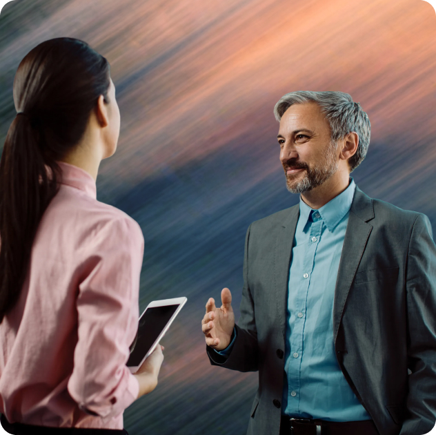 Man in suit speaking to woman holding a smartphone with abstract blurred background.