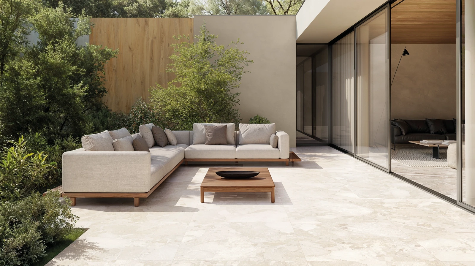 Terrasse mit hellen großformatigen Bodenplatten, Sitzgruppe und angrenzender Glasfront.