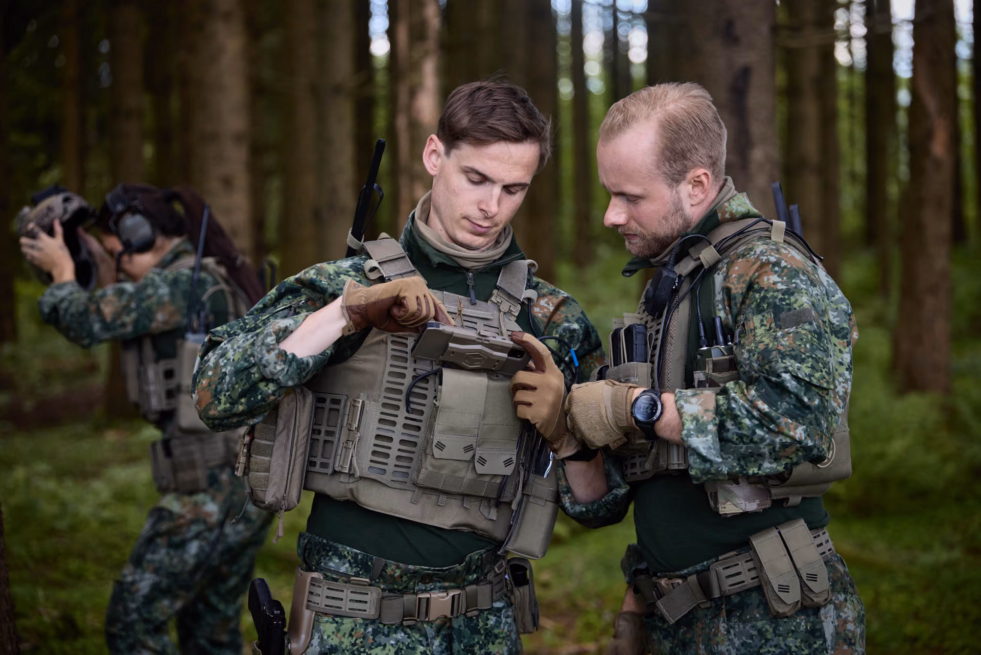 Drei Soldaten passen im Wald ihre taktischen THOR™ Schutzwesten an.