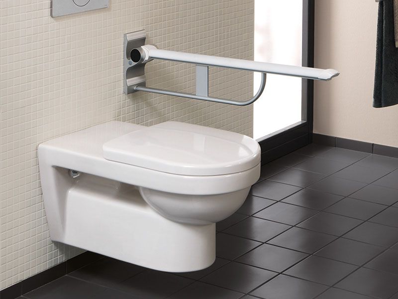 Wandhängendes, barrierefreies WC mit hochgeklapptem Stützgriff.