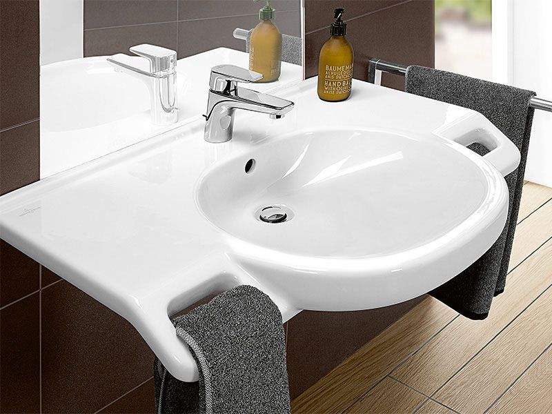 Ein unterfahrbares Waschbecken mit integrierten Handtuchhalterungen.