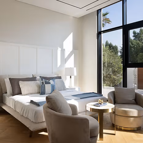 Bedroom interior with lounge seating and large windows by Emkaan