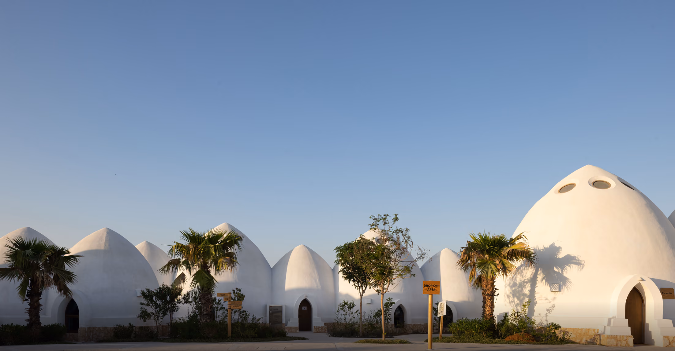 Cluster of domed structures with palm landscaping by Emkaan