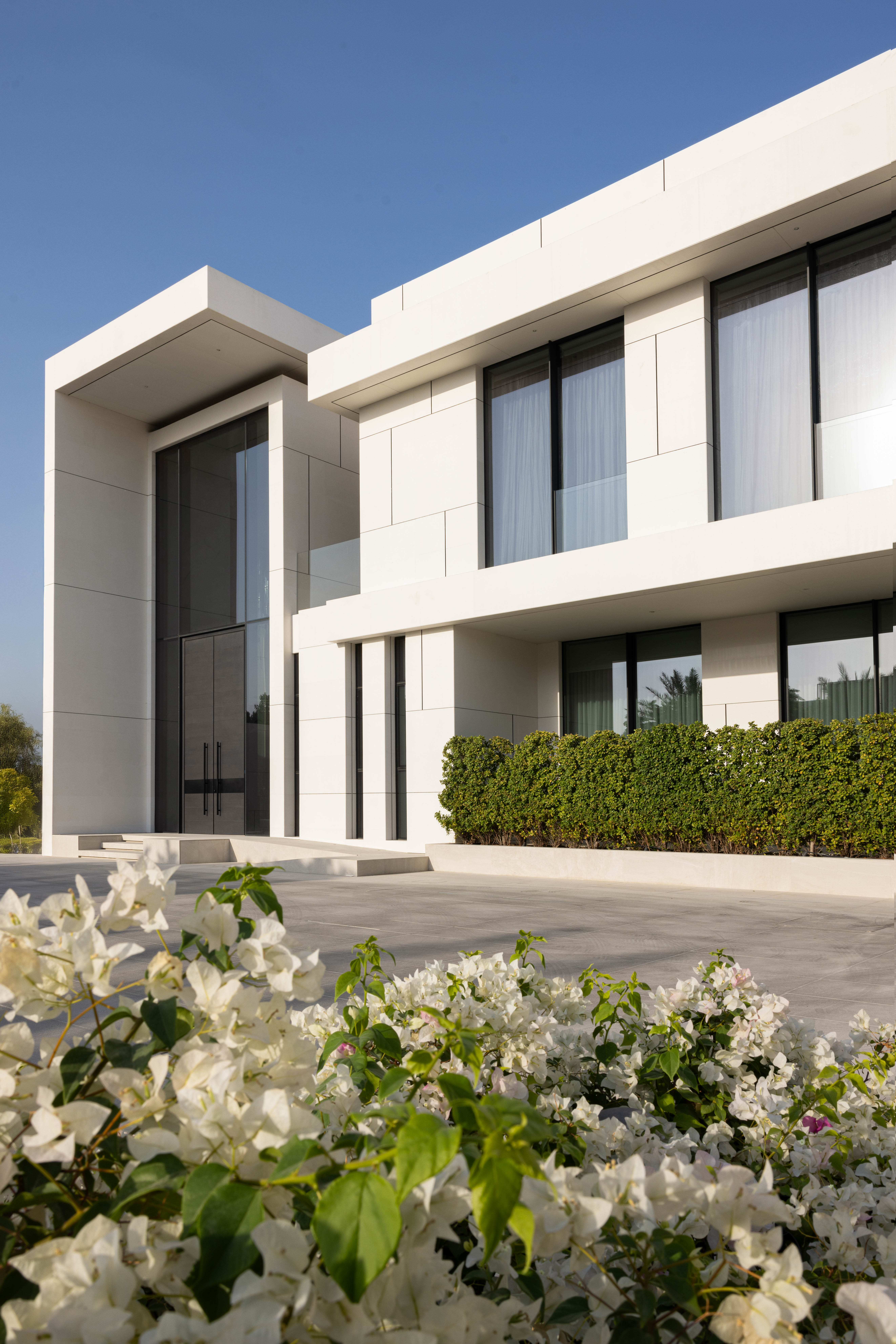 Contemporary villa exterior with flowering garden by Emkaan