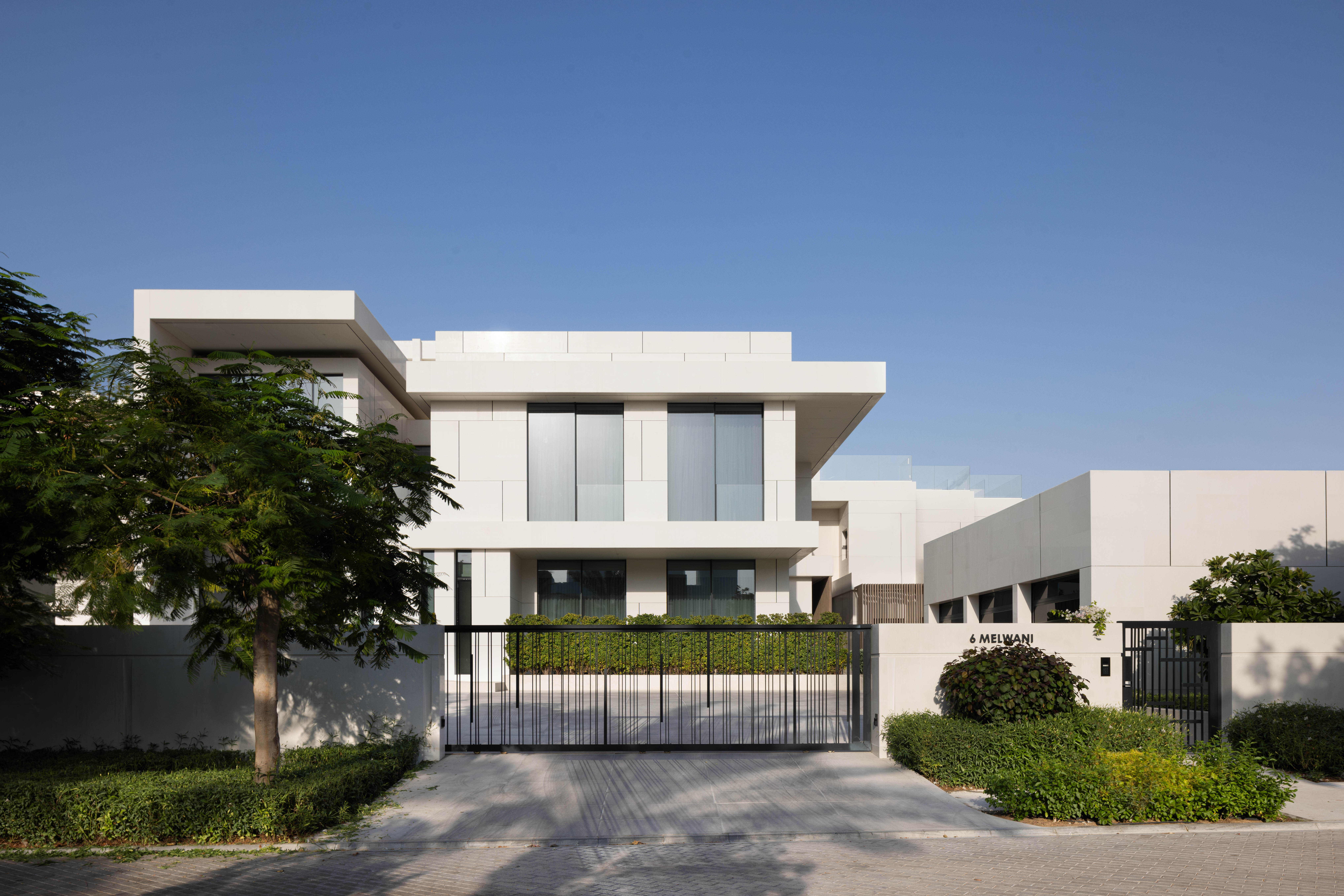 Luxury villa exterior with gated driveway by Emkaan