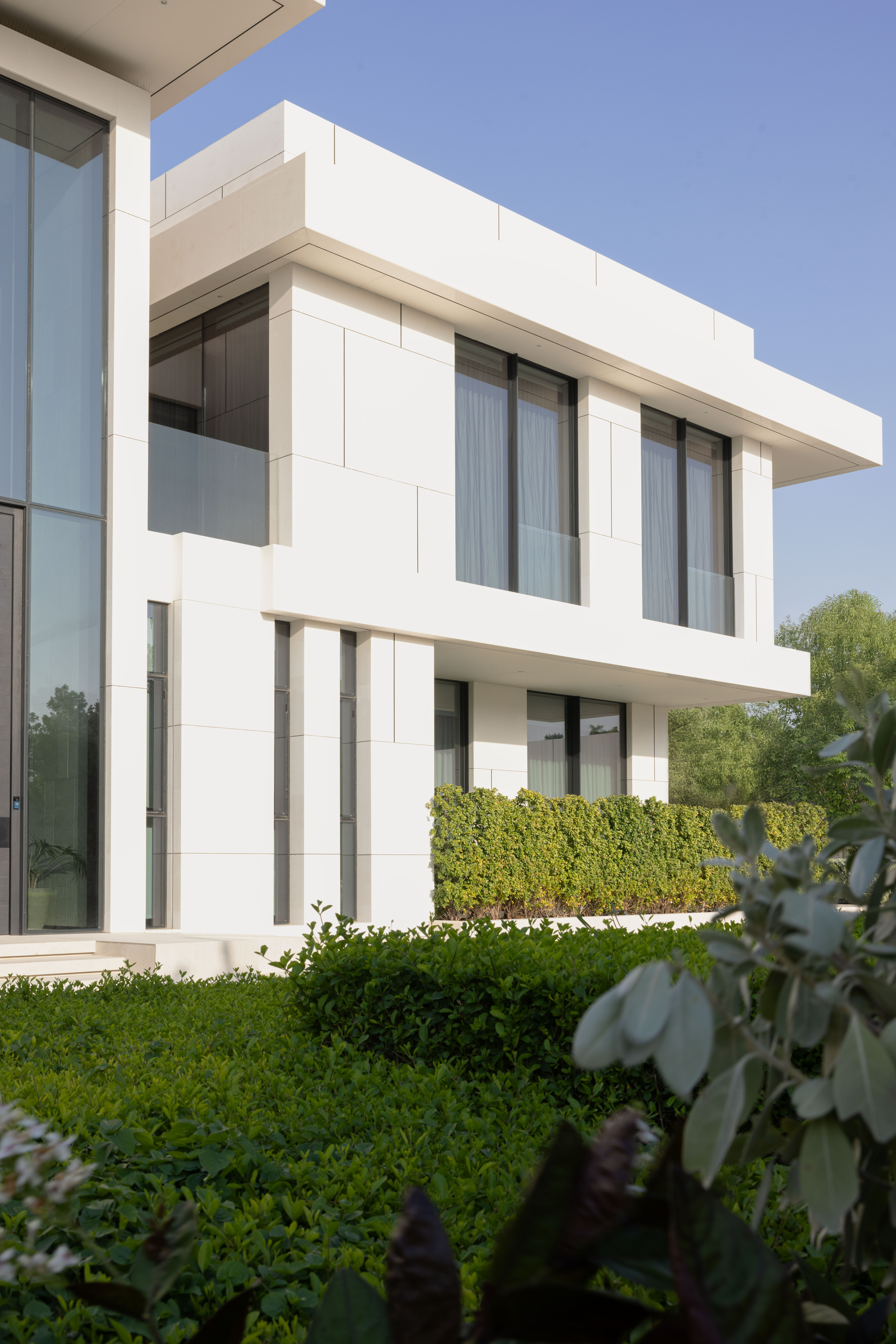 Modern white villa exterior with landscaped garden by Emkaan