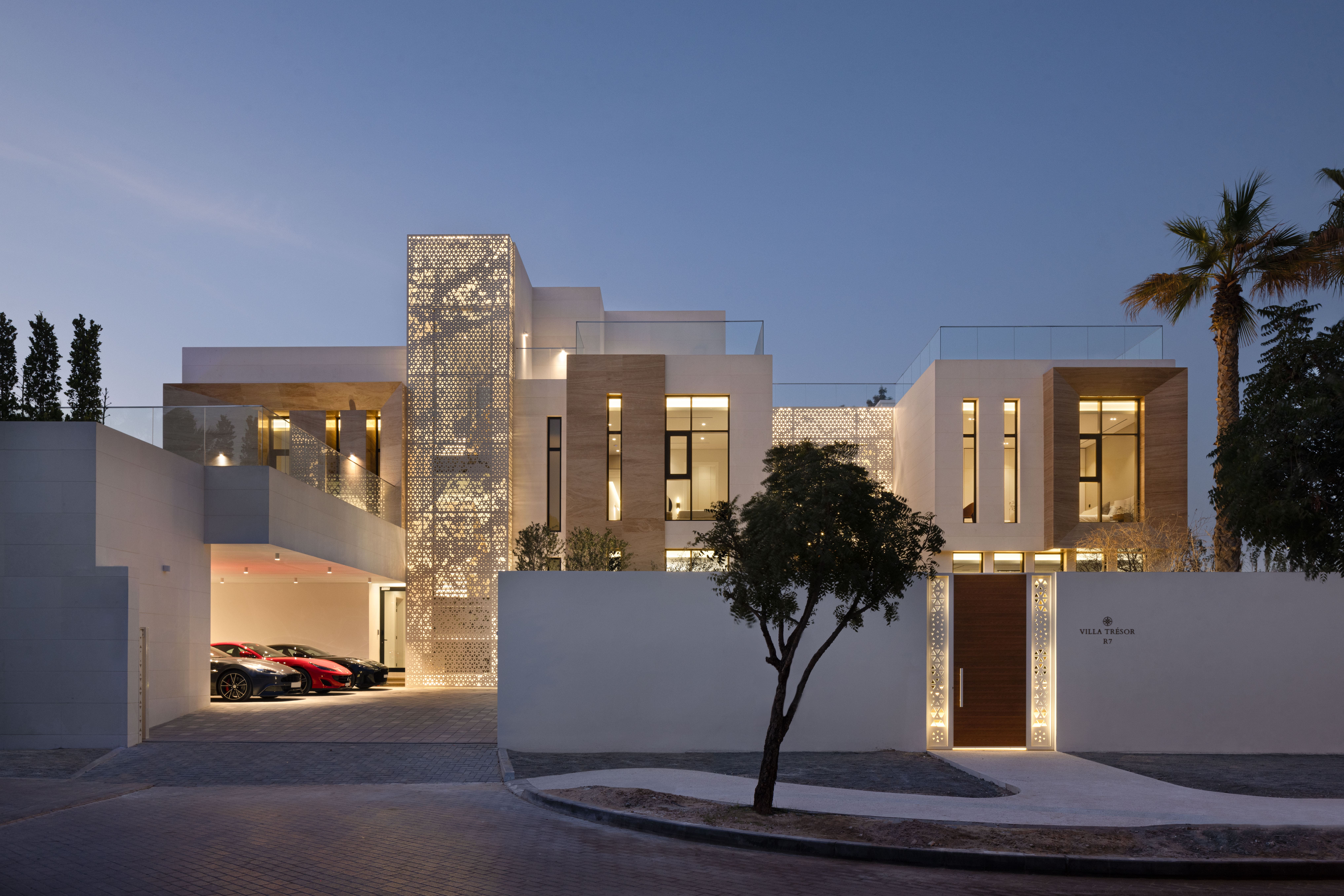 Contemporary villa exterior with landscaped entrance at twilight by Emkaan