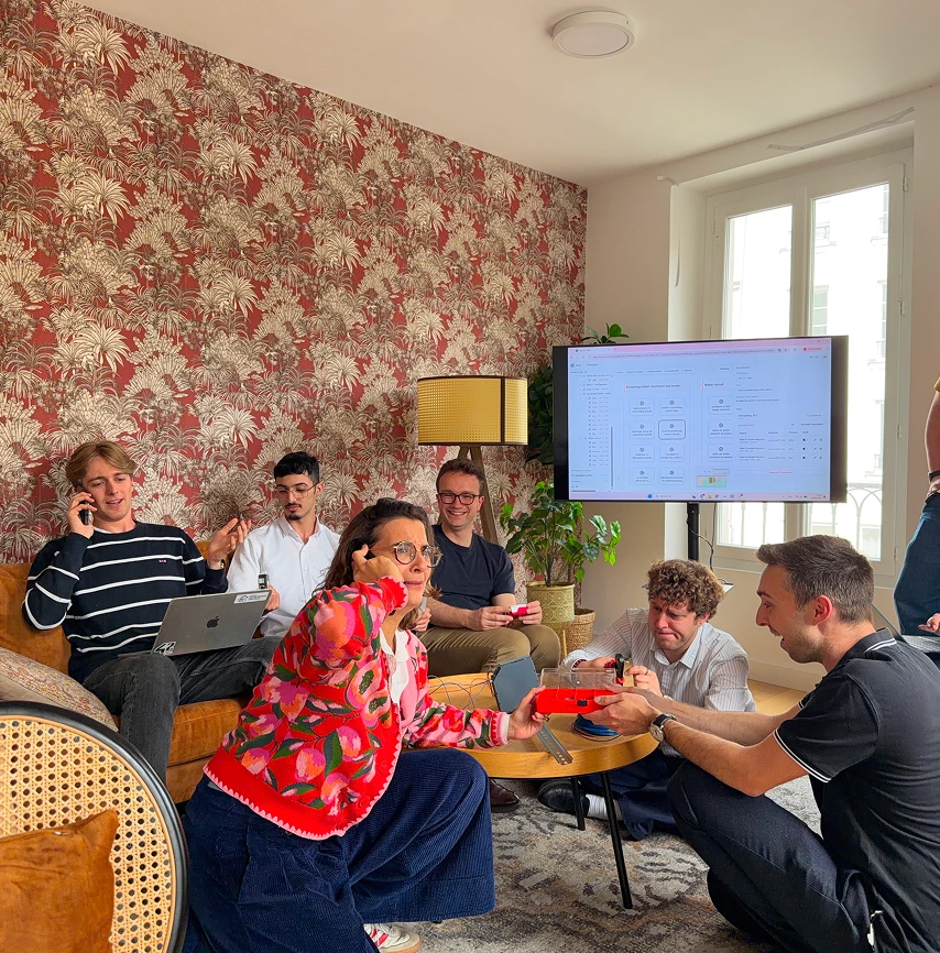 Six young people in a living room working and playing, with a computer screen showing data.