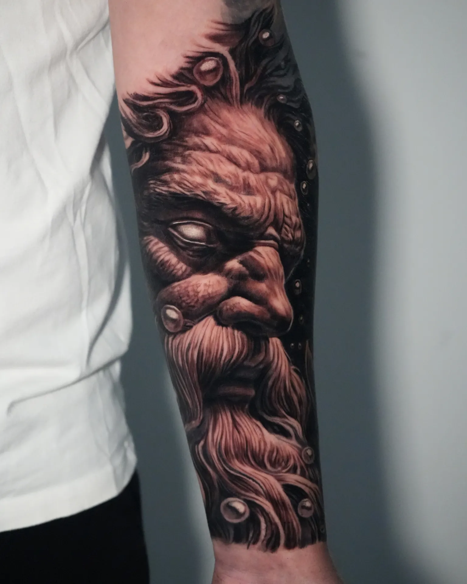 Realistisk underarms-tatovering af skægget gudeansigt i black and grey