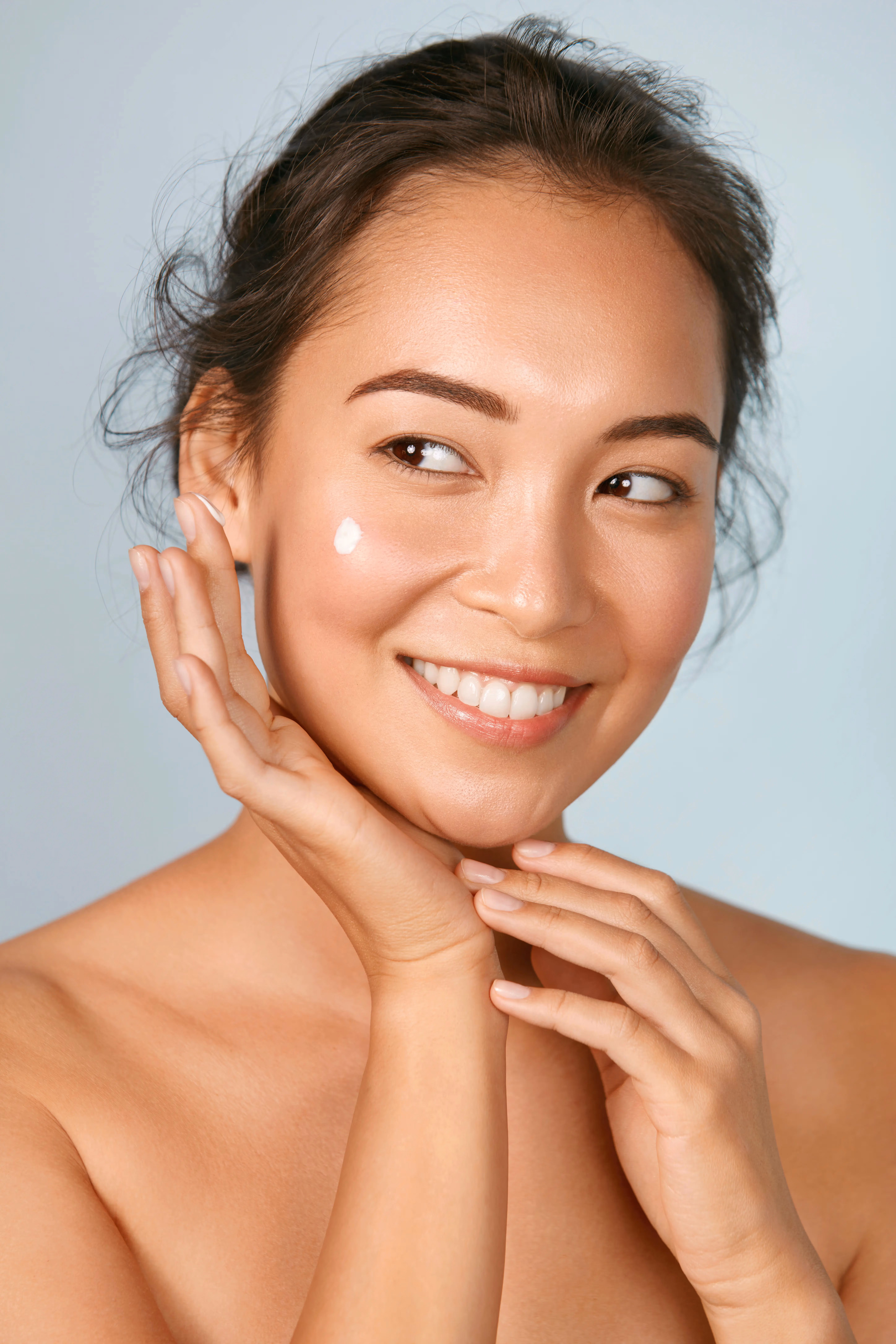 A woman smiling touching her face