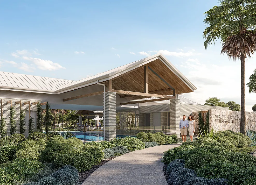 Couple walking on path near modern building with pool and landscaping under a clear blue sky.