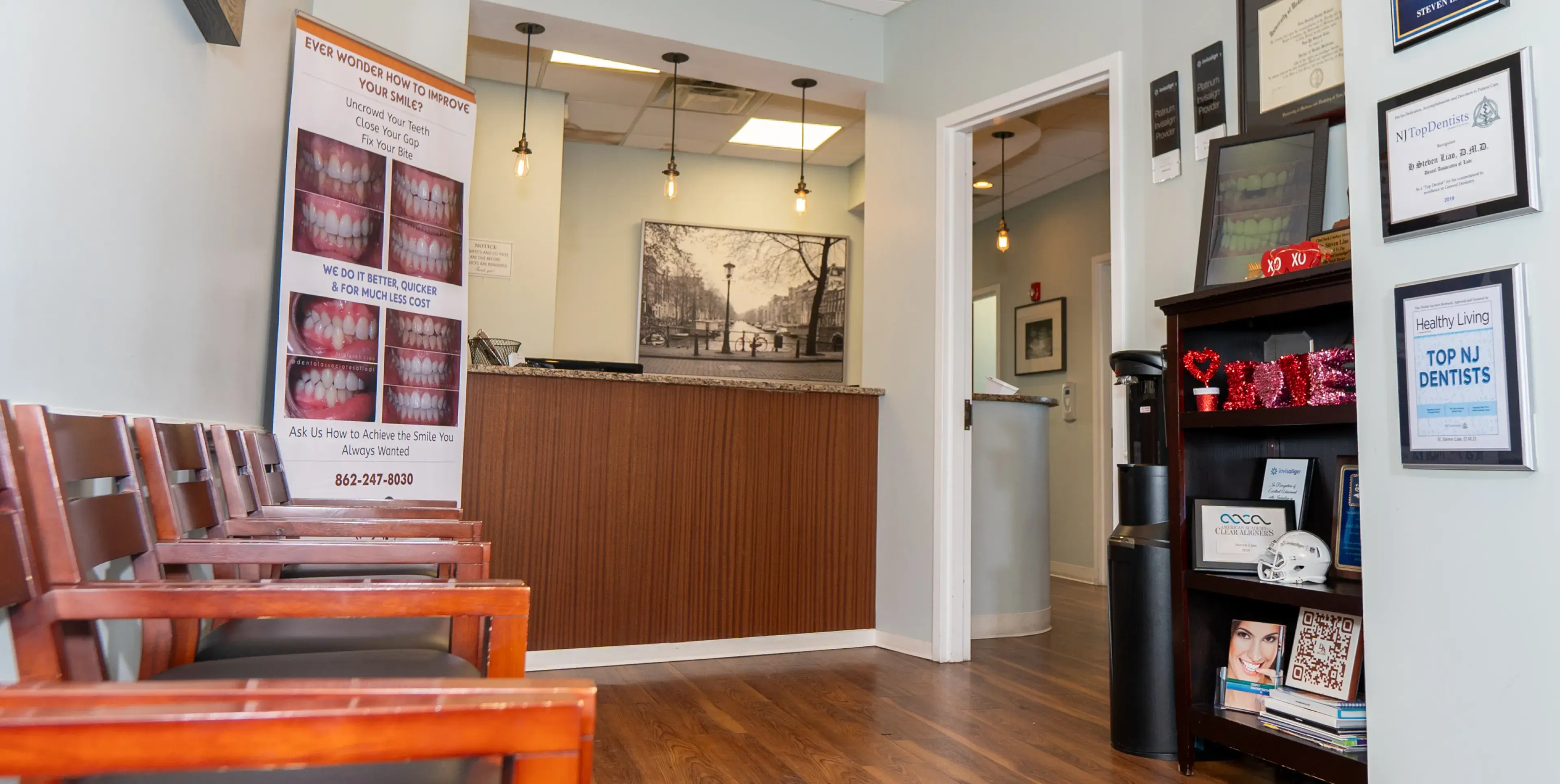 Dental office waiting area with wooden chairs, reception desk, and informational posters about dental services.