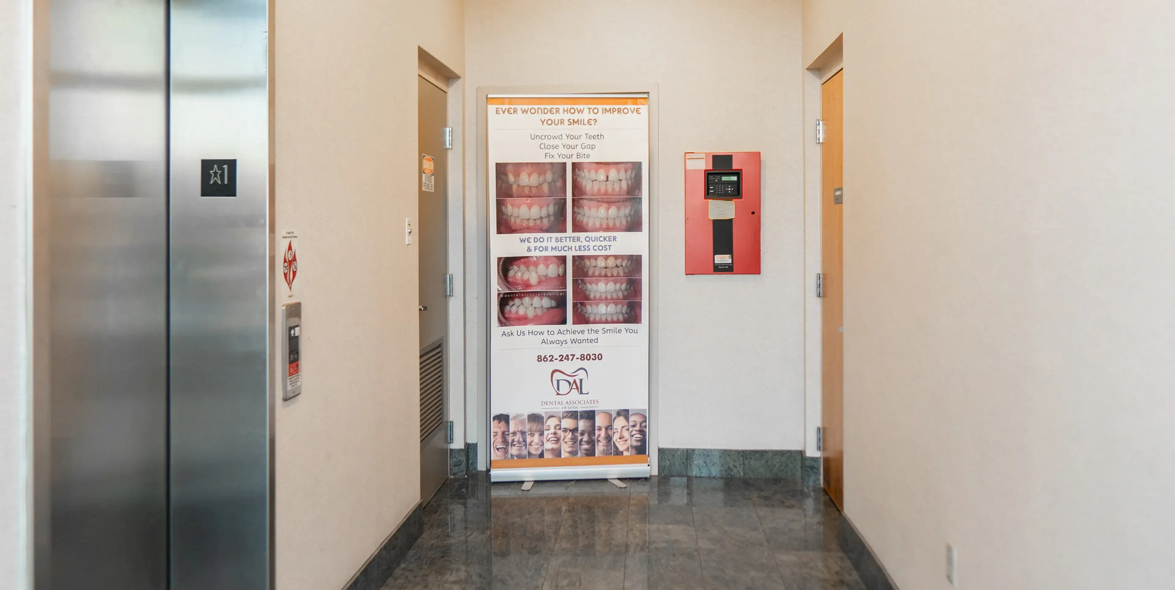 Roll-up banner in hallway displays dental advertising with images of close-up smiles.