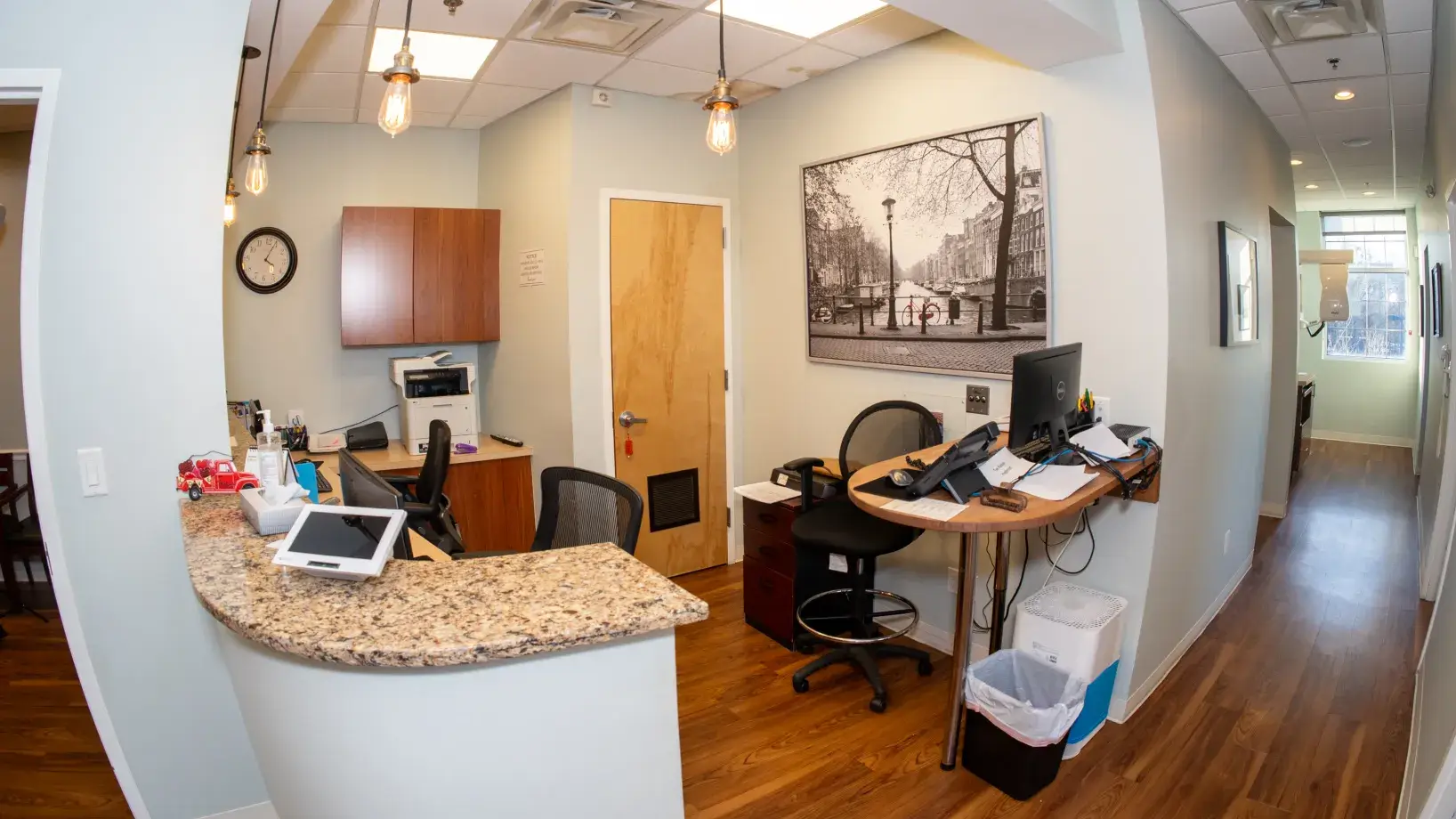 A small office reception area with a curved desk, computer, and chairs.
