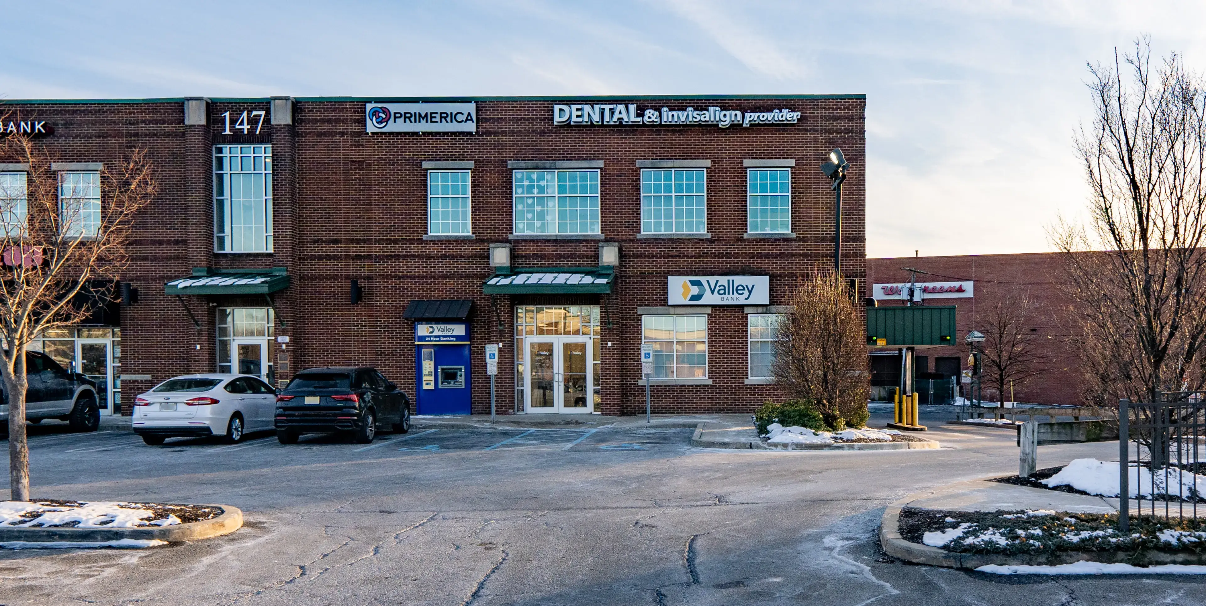 A small brick building with signs for a dental office and other businesses at the front.