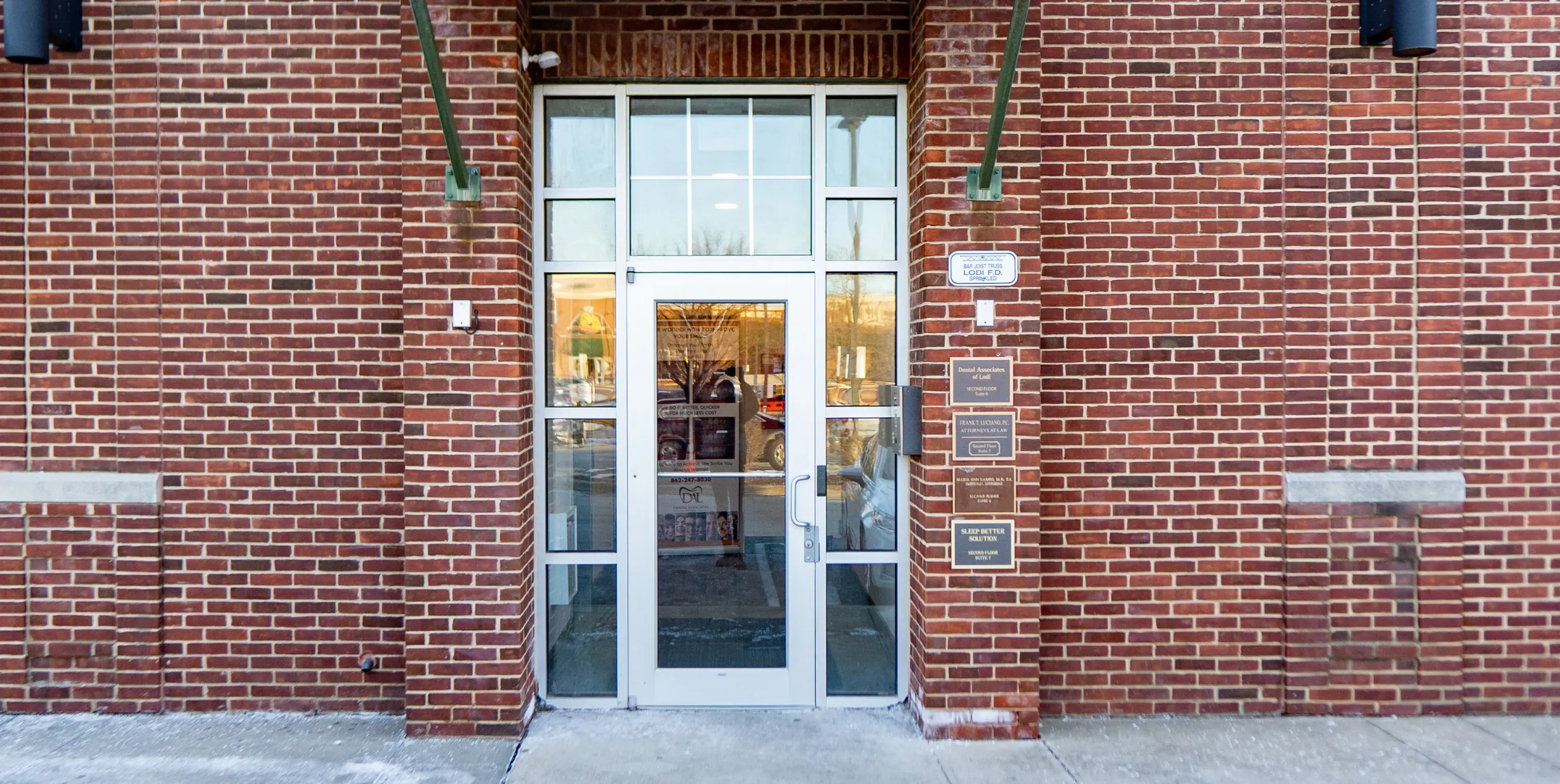 A glass door with a white frame set in a brick building entrance.